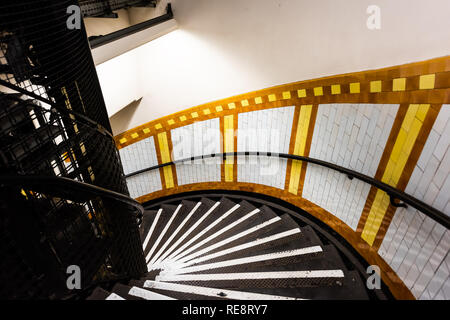 London, UK Covent Garden tube station underground spiral steps staircase down with nobody on stairs yellow colorful architecture Stock Photo