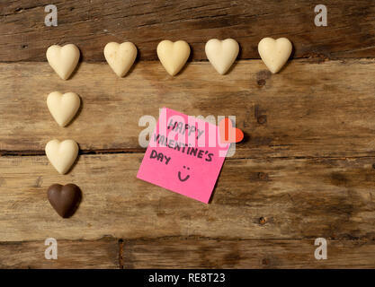 Beautiful top view Valentines composition of heart shaped chocolates and Happy Valentines day note written on post it in vintage style wooden table ba Stock Photo