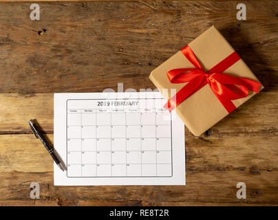 Conceptual image of 2019 february calendar and present gift wrapped with red ribbon on rustic vintage table in getting ready for saint Valentines day  Stock Photo