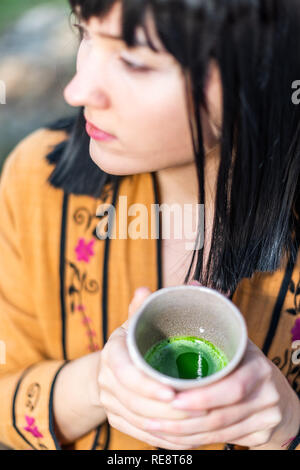 High angle view of woman holding tea cup face drinking outside in backyard garden with girl eyes and black hair Stock Photo