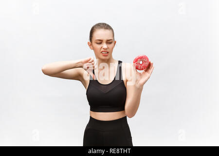 Beautiful young woman over grey background eating donut stressed with hand on head, shocked with shame and surprise face, angry and frustrated. Fear and upset for mistake Stock Photo