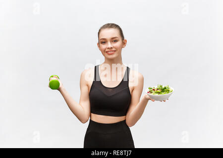Sport, healthy lifestyle, people concept - young brunette woman with salad and a dumbbell. She is smiling and enjoying the healthy lifestyle. Stock Photo