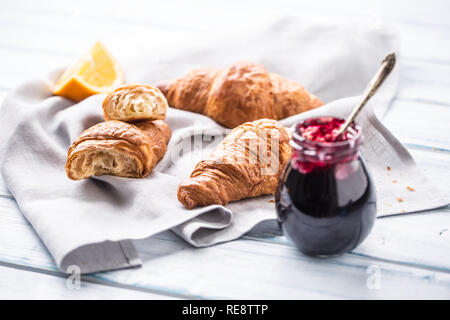 Fresh buttery croissants marmalade and oranges on kitchen table. Stock Photo