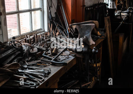 Vintage tools sit on a workbench, lit from a nearby window Stock Photo