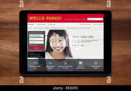 The website of Wells Fargo is seen on an iPad tablet, which is resting on a wooden table (Editorial use only). Stock Photo