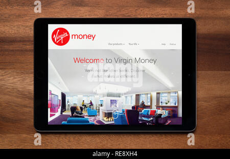 The website of Virgin Money is seen on an iPad tablet, which is resting on a wooden table (Editorial use only). Stock Photo