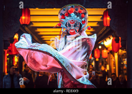 Chengdu, Sichuan Province, China - Jan 19, 2019: Chinese actress performs a public traditional face-changing art or bianlian onstage at Chunxifang Chunxilu covered street. Stock Photo