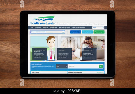 The website of South West Water is seen on an iPad tablet, which is resting on a wooden table (Editorial use only). Stock Photo