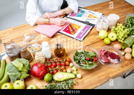 Dietitian writing diet plan, view from above on the table with different healthy products and drawings on the topic of healthy eating Stock Photo