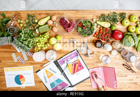 Dietitian writing diet plan, view from above on the table with different healthy products and drawings on the topic of healthy eating Stock Photo