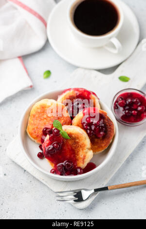 Syrniki, cottage cheese fritters with berry sauce and cup of black coffee. Top view, selective focus Stock Photo