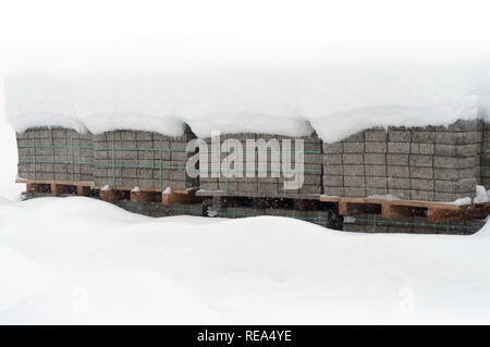 A view of bricks under snow. Snow cover stack of brick. Construction bricks under snow after a winter cyclone in Europe Stock Photo