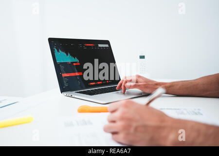 Businessman analyze digital reports on screen monitor and preparing financial report for investors. Close up view of male manager sitting at desktop a Stock Photo