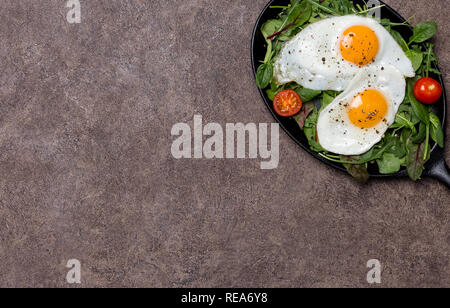 Free space with fried eggs and fresh herbs at black frying pan. Free space for your text. Concept of healthy lifestyle