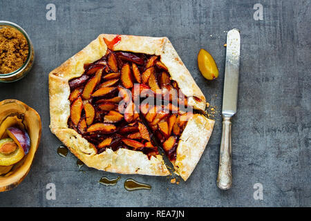 Plum pie or tart and ingredients flat lay. Seasonal Fall or Autumn dessert Stock Photo