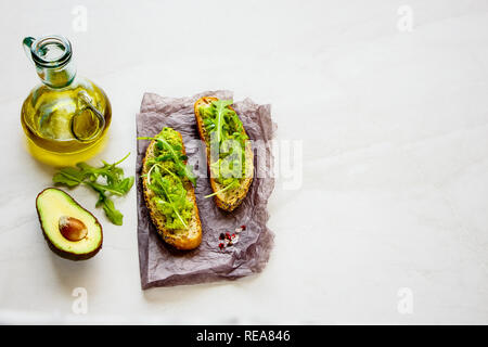 Fresh avocado toasts with arugula close up. Good fats raw healthy eating concept. Stock Photo
