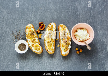 Flat-lay of toasts with ricotta cheese, banana and nuts Stock Photo