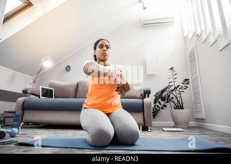 African American woman with tied hair doing special exercise for palms Stock Photo