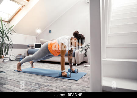 Confident strict African American lady using dumbbells during training Stock Photo