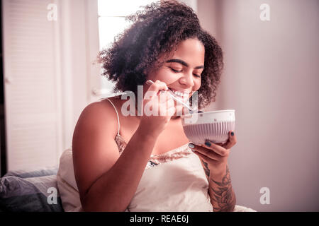 Dark-haired young lady being contented during breakfast