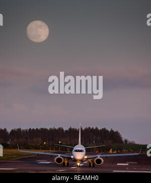 Cork, Ireland. 20th January, 2019. An embraer 190 jet aircraft operated by Hop Airlines taxiis on runway 16/34 prior to take off to Paris while a full super wolf moon rises at Cork Airport, Cork, Ireland. Credit: David Creedon/Alamy Live News Stock Photo