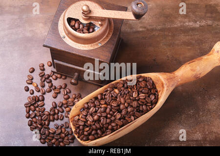 coffee beans in a wooden scoop and coffee grinder on dark stone table. Stock Photo
