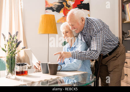 Side view portrait of modern elderly couple using laptop at home while online-shopping together, copy space Stock Photo