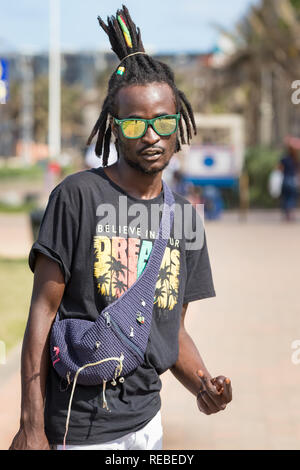 Durban, South Africa - January 07th, 2019: Portrait of a young black african man wearing sunglasses and rasta-dreadlooks hair style in the center of D