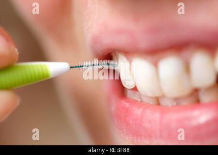 Young woman brushing her teeth with a special interdental toothbrush Stock Photo