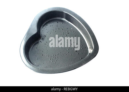 Metal heart shaped baking dish isolated on white background. Oil droplets Stock Photo