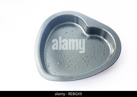 Metal heart shaped baking dish isolated on white background. Oil droplets Stock Photo
