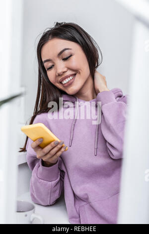 Beaming appealing woman feeling happy receiving message from boyfriend Stock Photo
