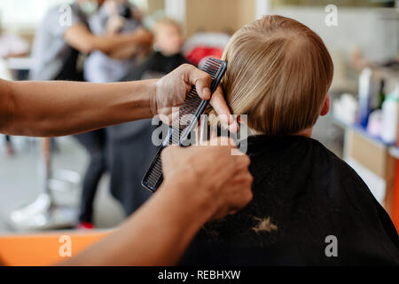 Crop barber doing haircut to little boy Stock Photo