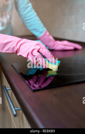 Picture of female hands in pink rubber gloves washing hob Stock Photo