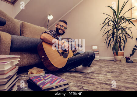 Cheerful happy man sitting with his guitar Stock Photo