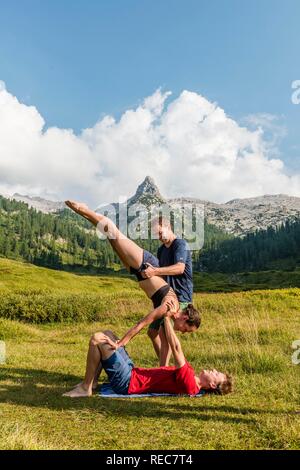 Young woman and young man doing acro yoga, mountain landscape, Berchtesgaden National Park, Berchtesgadener Land, Upper Bavaria Stock Photo