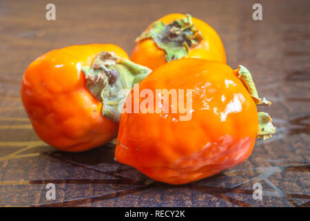 Close up of bright orange Persimmons fruit kept on a wooden table Stock Photo