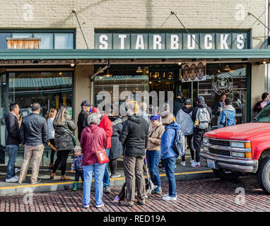Seattle, Washington, USA - 28 October 2018. Customers queuing along the sidewalk outside the original Starbucks coffee house at 1912 Pike Place.