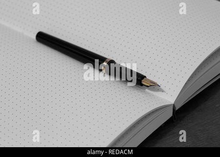 Bullet journal with blank pages and a fountain pen in the middle on a wood background Stock Photo