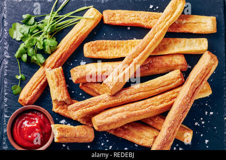 Cheese Straws, Cheesy Bread Sticks on a cutting wooden board with tomato sauce on a stone treay, view from above, close-up, flatlay Stock Photo