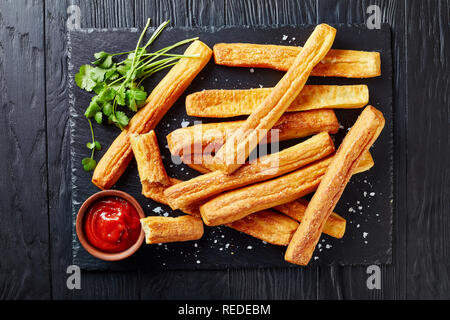 Cheese Straws, Cheesy Bread Sticks on a cutting wooden board with tomato sauce on a stone treay, view from above, close-up, flatlay Stock Photo