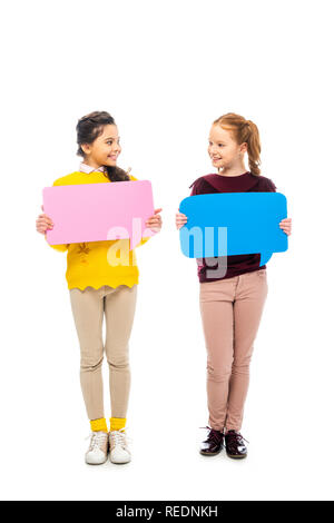 cheerful schoolgirls holding multicolored speech bubbles and looking at each other isolated on white Stock Photo