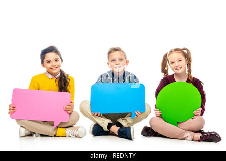 smiling kids sitting, holding multicolored speech bubbles and looking at camera isolated on white Stock Photo