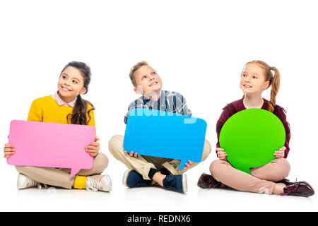 cheerful kids sitting and holding multicolored speech bubbles isolated on white Stock Photo