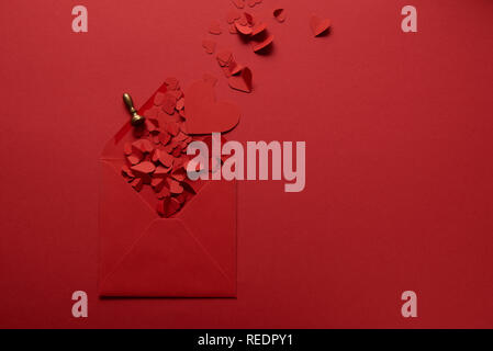 top view of paper cut hearts and opened envelope on red background Stock Photo