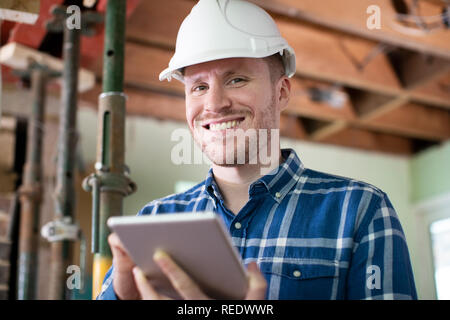 Portrait Of Architect Inside House Being Renovated Using Digital Tablet Stock Photo