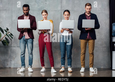 concentrated multiethnic casual businesspeople using laptops in waiting hall Stock Photo