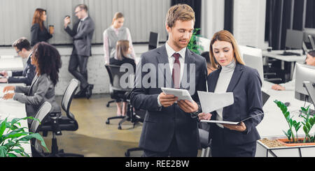 professional young business colleagues discussing papers while standing together in open space office Stock Photo