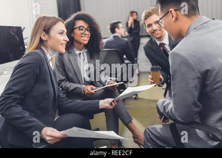 smiling young multiracial business people holding documents and discussing project in office Stock Photo
