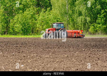 Verhovina, Russia - June 30, 2017: Farmer with tractor seeding - sowing crops at agricultural fields Stock Photo